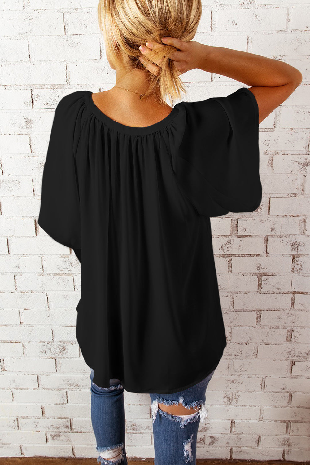Black relaxed V-neck blouse with cap sleeves and gathered neckline detail.