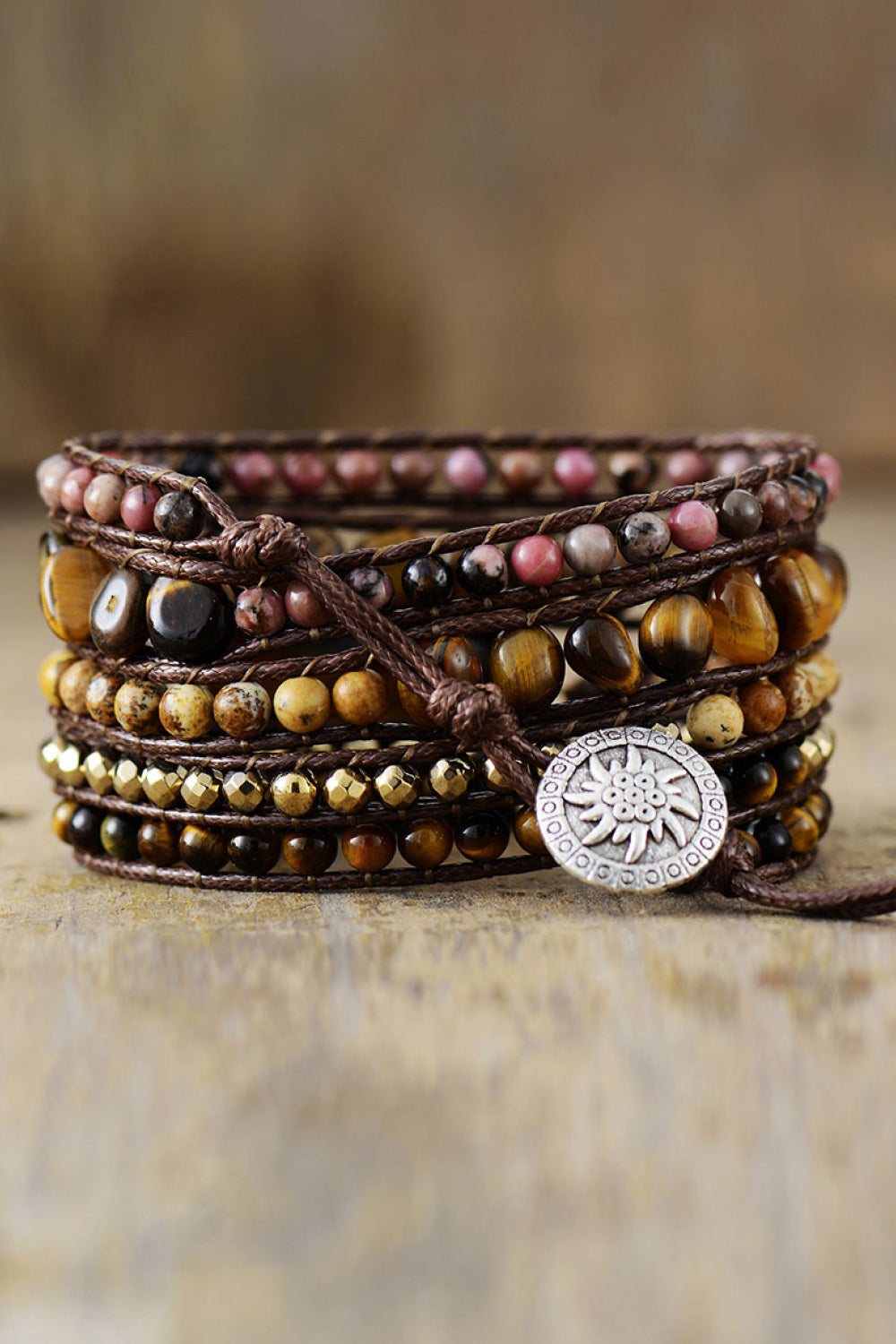Wrap bracelet stack with tiger eye, pink stone, and gold beads on brown cord with silver charm.