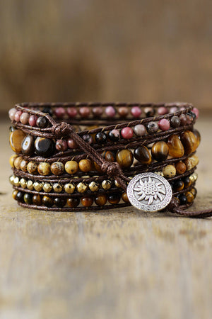 Wrap bracelet stack with tiger eye, pink stone, and gold beads on brown cord with silver charm.