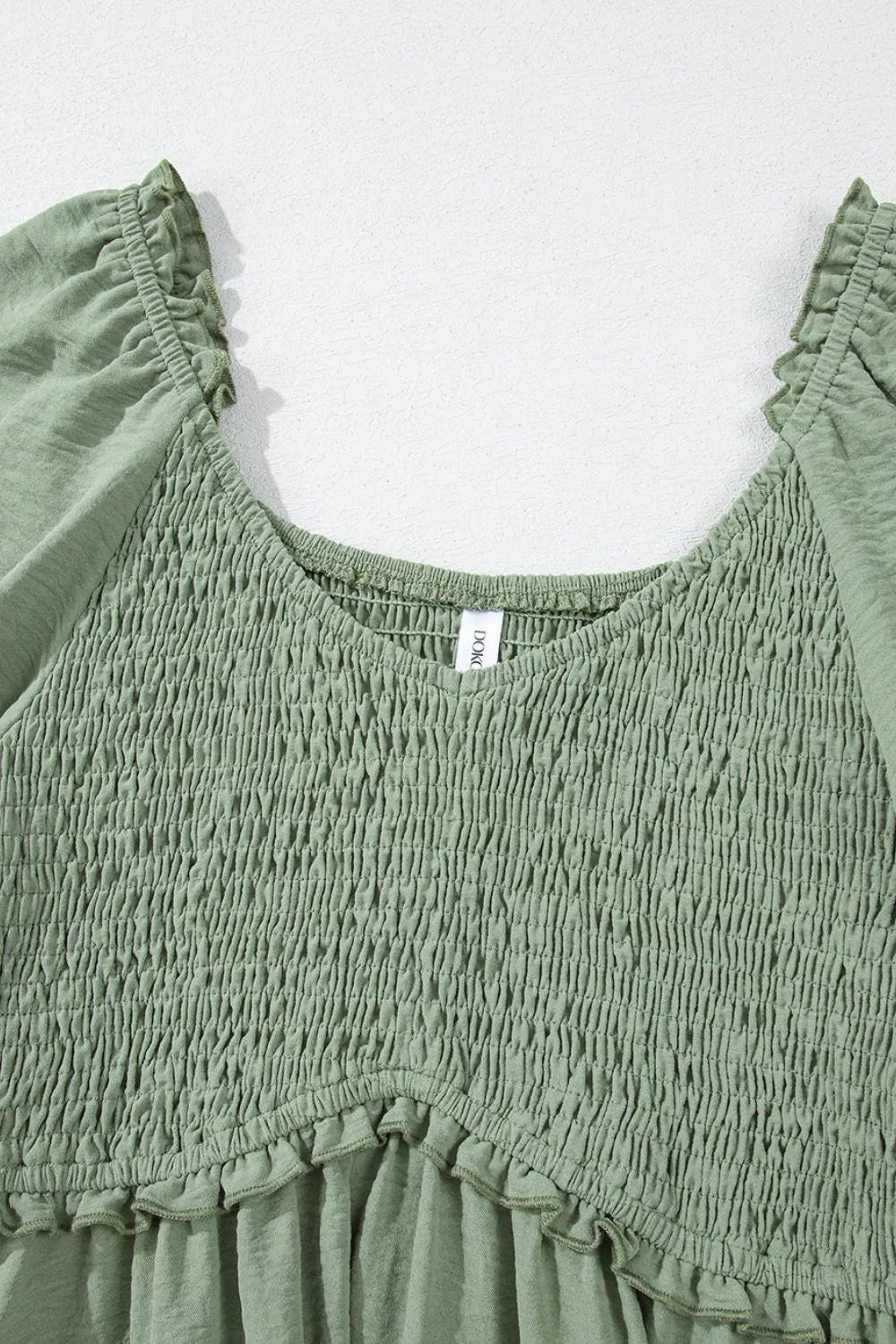 Sage smocked mini dress with V-neck, frill trim, and short sleeves.