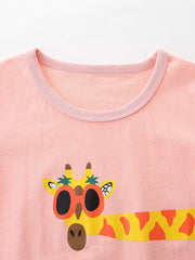Pink cotton crew neck toddler t-shirt with a fun giraffe graphic wearing sunglasses.