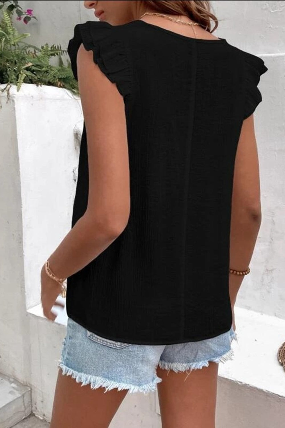 Black flutter sleeve blouse with embroidered trim detail.