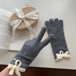 Dark gray knit gloves with cream bows and decorative buttons.