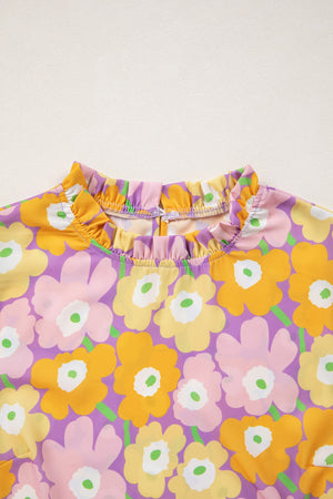 Puff sleeve blouse with ruffle trim and a bold floral print in purple, yellow, pink, and green.