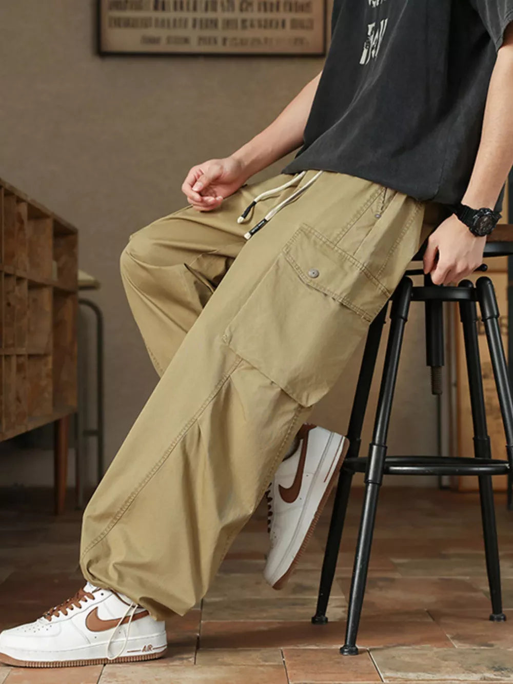Khaki drawstring cargo pants for men with button-down flap pockets and adjustable waist.