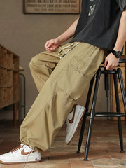 Khaki drawstring cargo pants for men with button-down flap pockets and adjustable waist.