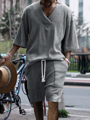 Men's light gray cable-knit v-neck two-piece set with drawstring shorts.