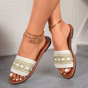 White embroidered artisan open-toe sandals with gold detailing and brown soles.