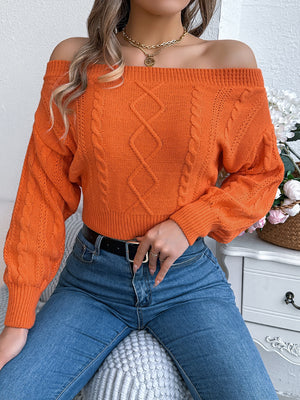 Orange cable knit off-shoulder crop sweater with diamond pattern and cuffed sleeves.