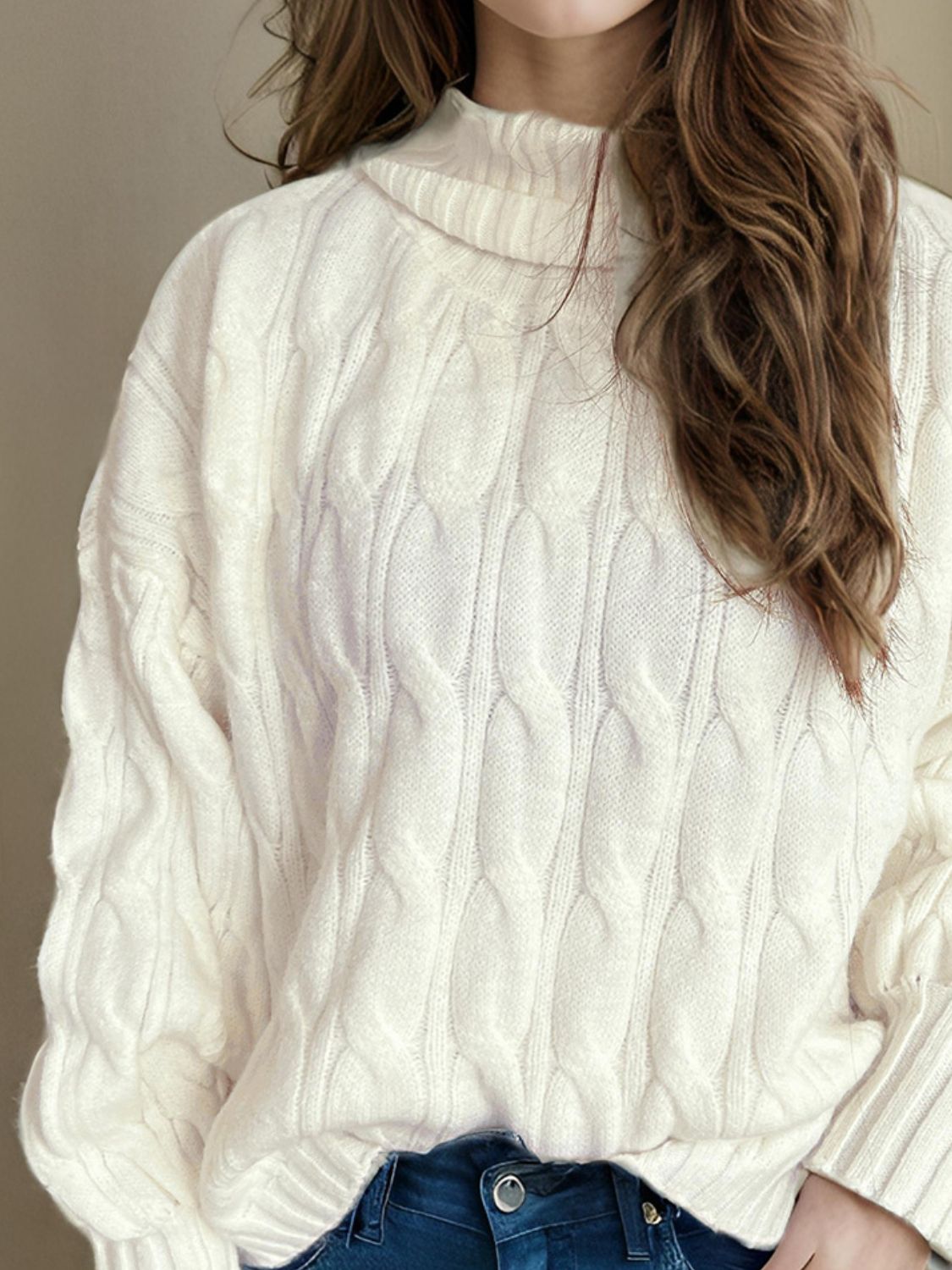 Ivory oversized cable knit turtleneck sweater with prominent cable detailing.