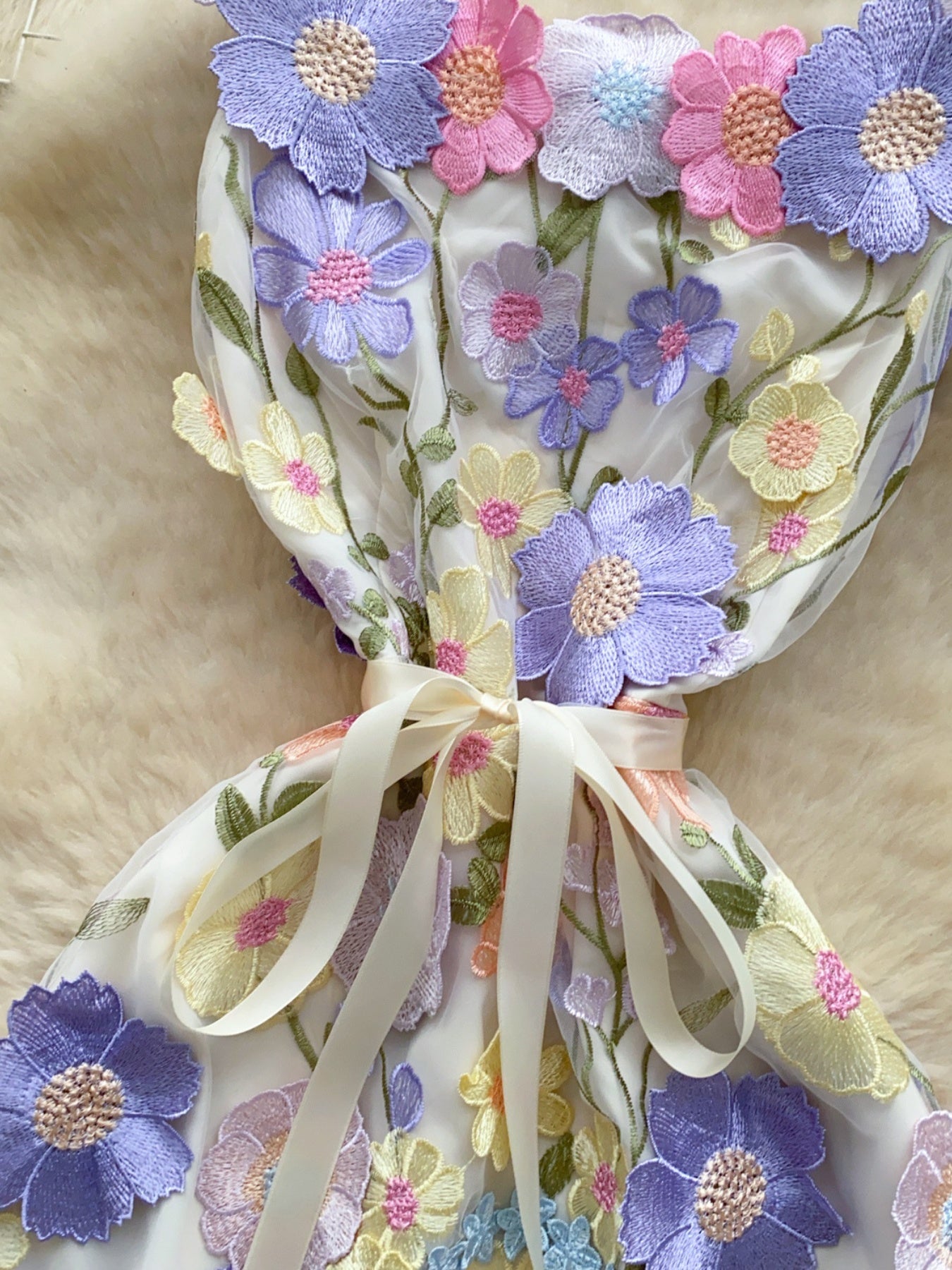 Embroidered floral mini dress in white with colorful flower appliques and a ribbon bow detail.