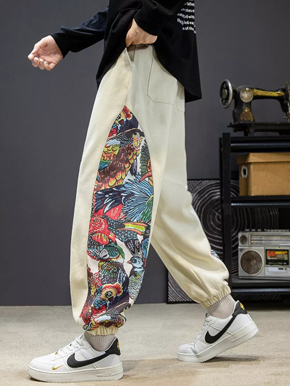 Men's off white joggers with vibrant bird print side panels and elastic cuffs.