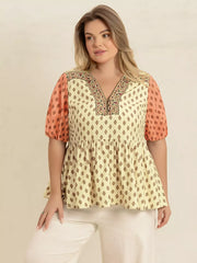 Vibrant geometric peplum shirt with coral puff sleeves and a v-neck with zipper detail.