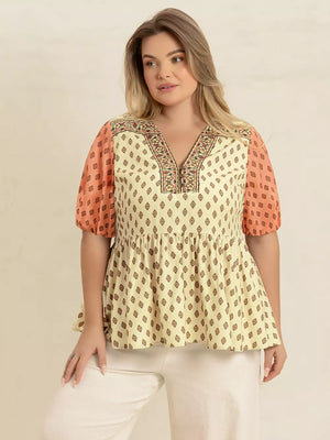 Vibrant geometric peplum shirt with coral puff sleeves and a v-neck with zipper detail.