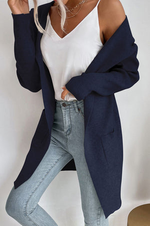 Navy ribbed knit hooded cardigan with drape front and pockets, worn over a white cami and jeans.