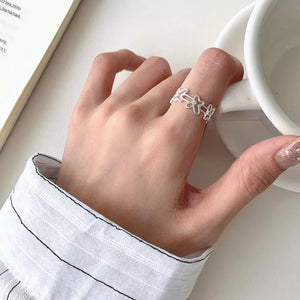 Sterling silver open ring with delicate floral motif and small center stone.
