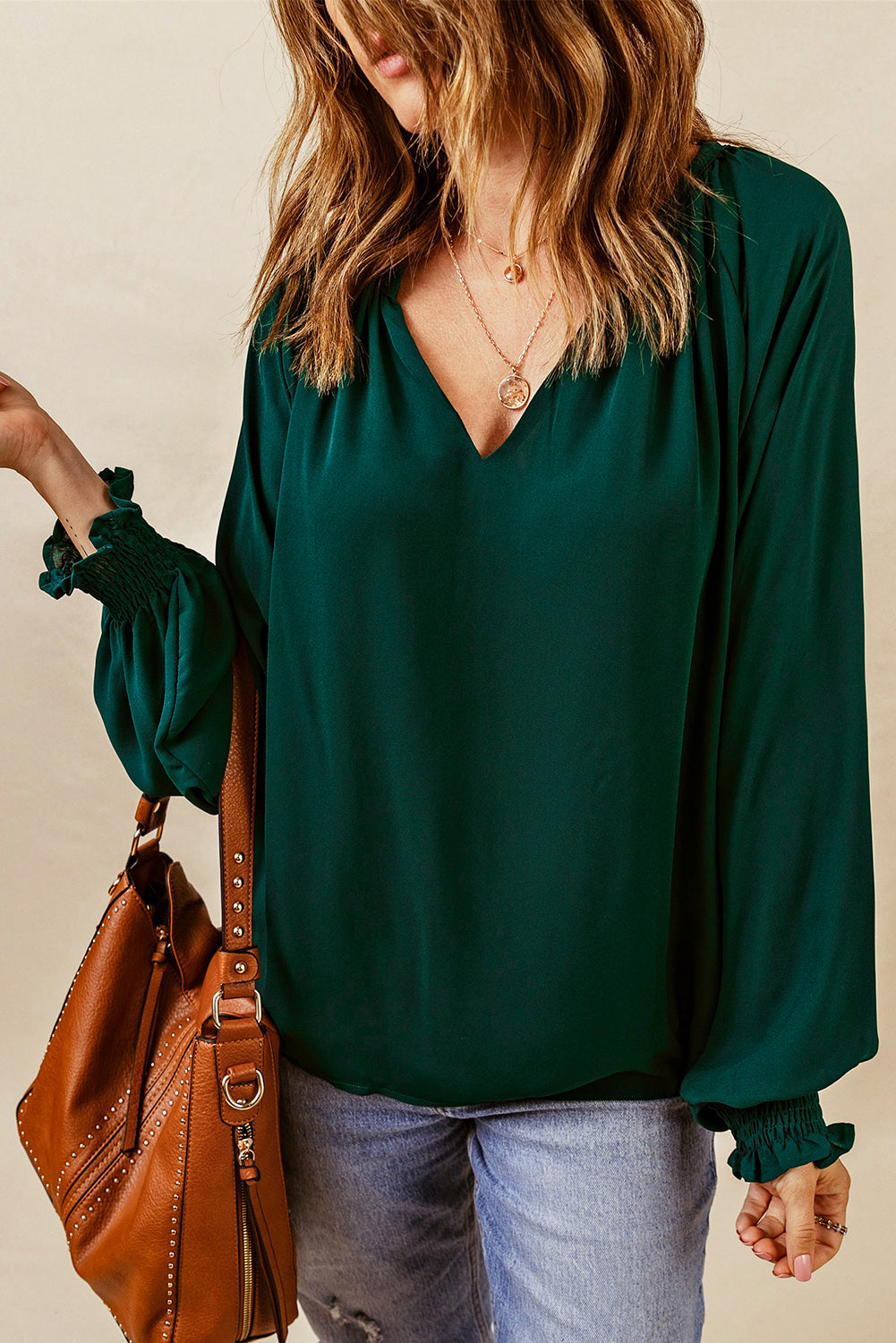 Green blouse with V-neck, voluminous sleeves, and ruched cuffs.