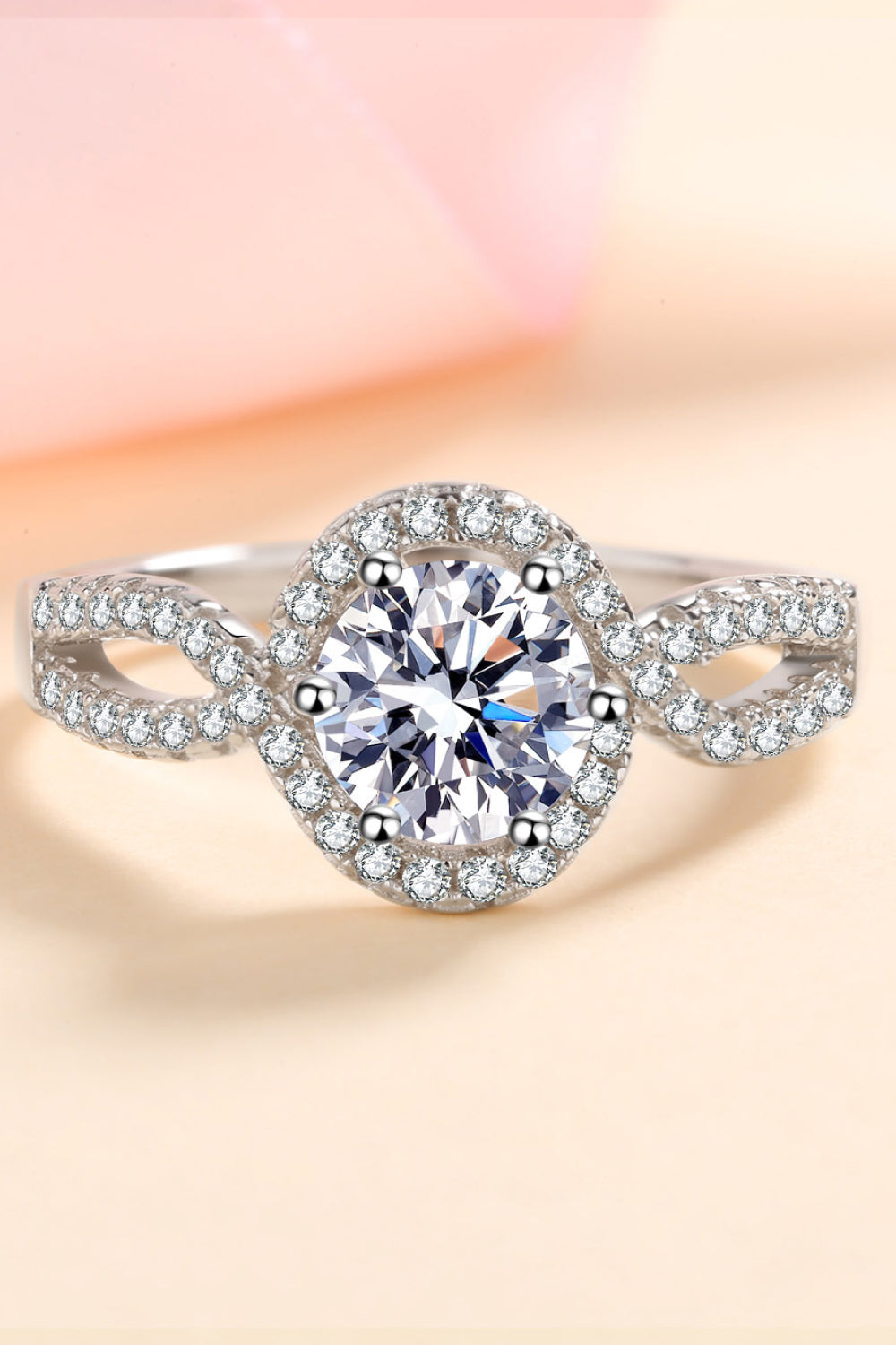Silver moissanite engagement ring with halo and infinity band.