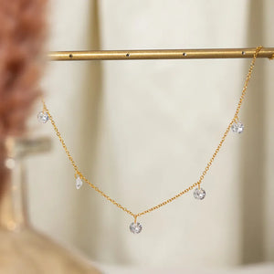 Gold dangling crystal station necklace with a delicate chain and five clear cubic zirconia stones.