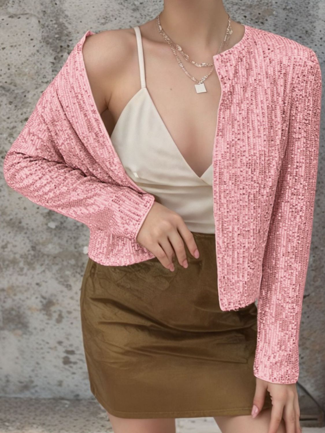 Blush pink sequin bolero jacket with long sleeves and open front, worn over a camisole.