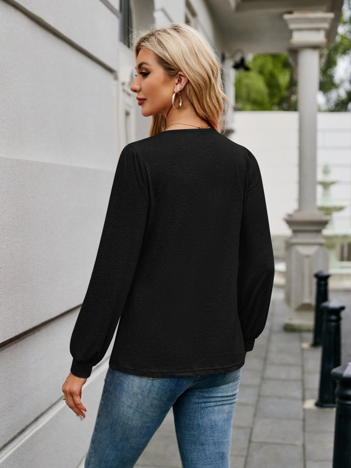 Black long sleeve top with gathered sleeves and a relaxed fit, styled with jeans.