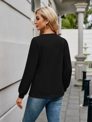 Black long sleeve top with gathered sleeves and a relaxed fit, styled with jeans.