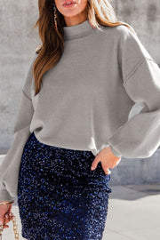 Gray mock neck knit sweater with balloon sleeves and visible seams.