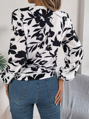 White floral knot-front blouse with ruffled cuffs and long sleeves.