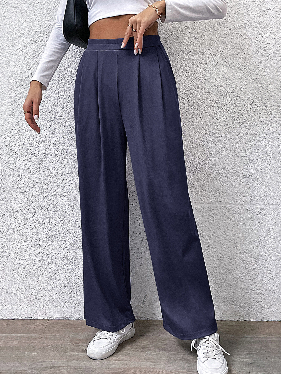 Navy pleated front wide leg trousers with a high waist, styled casually.