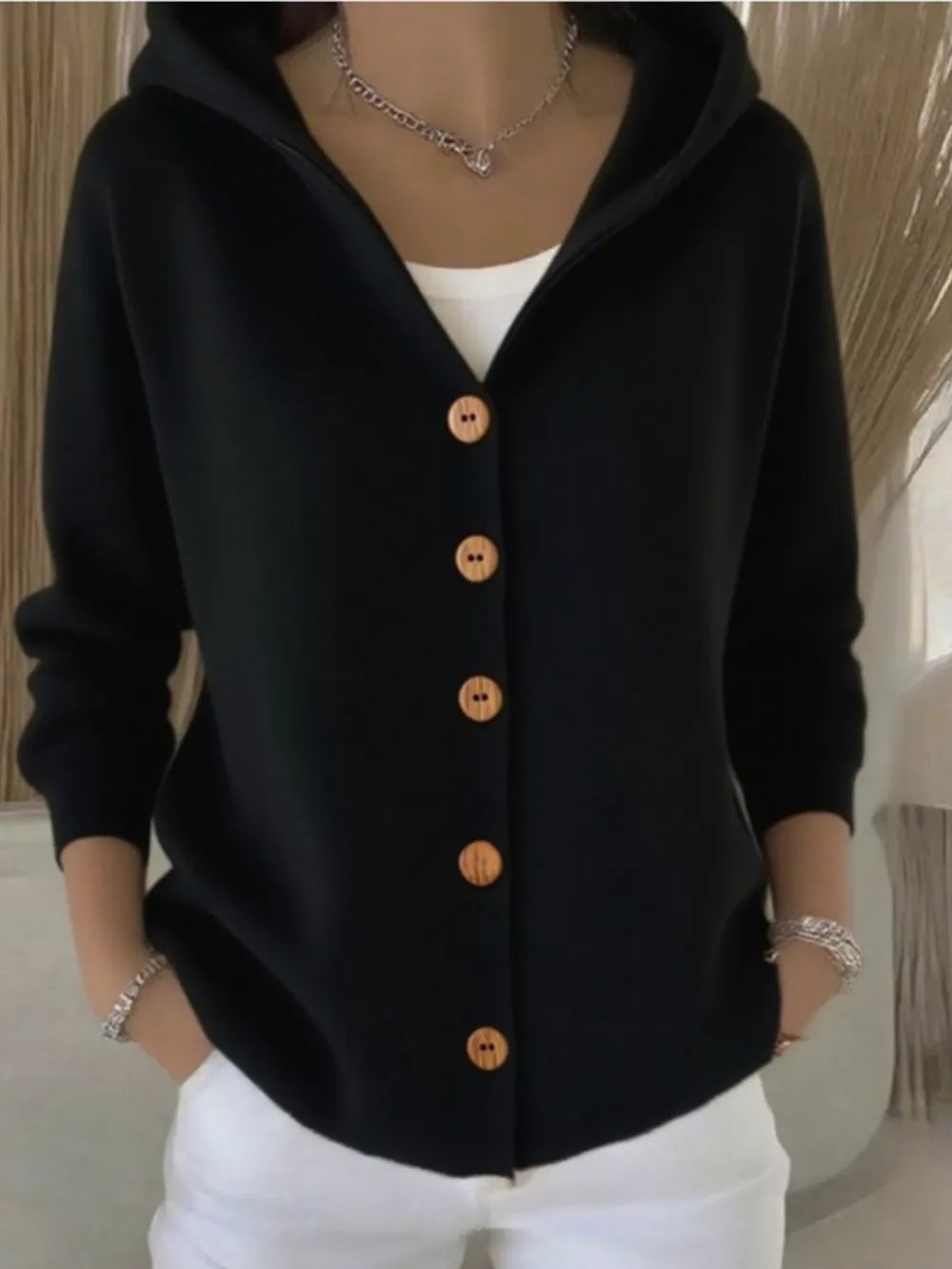 Black hooded knit cardigan with wooden buttons and white tank top.