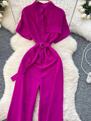Chic belted wide leg romper in rose red with short sleeves and button-down front.
