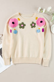 Cream knit sweater with embroidered floral appliqués and ribbed trim.