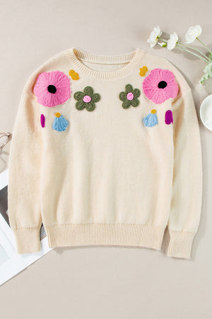 Cream knit sweater with embroidered floral appliqués and ribbed trim.