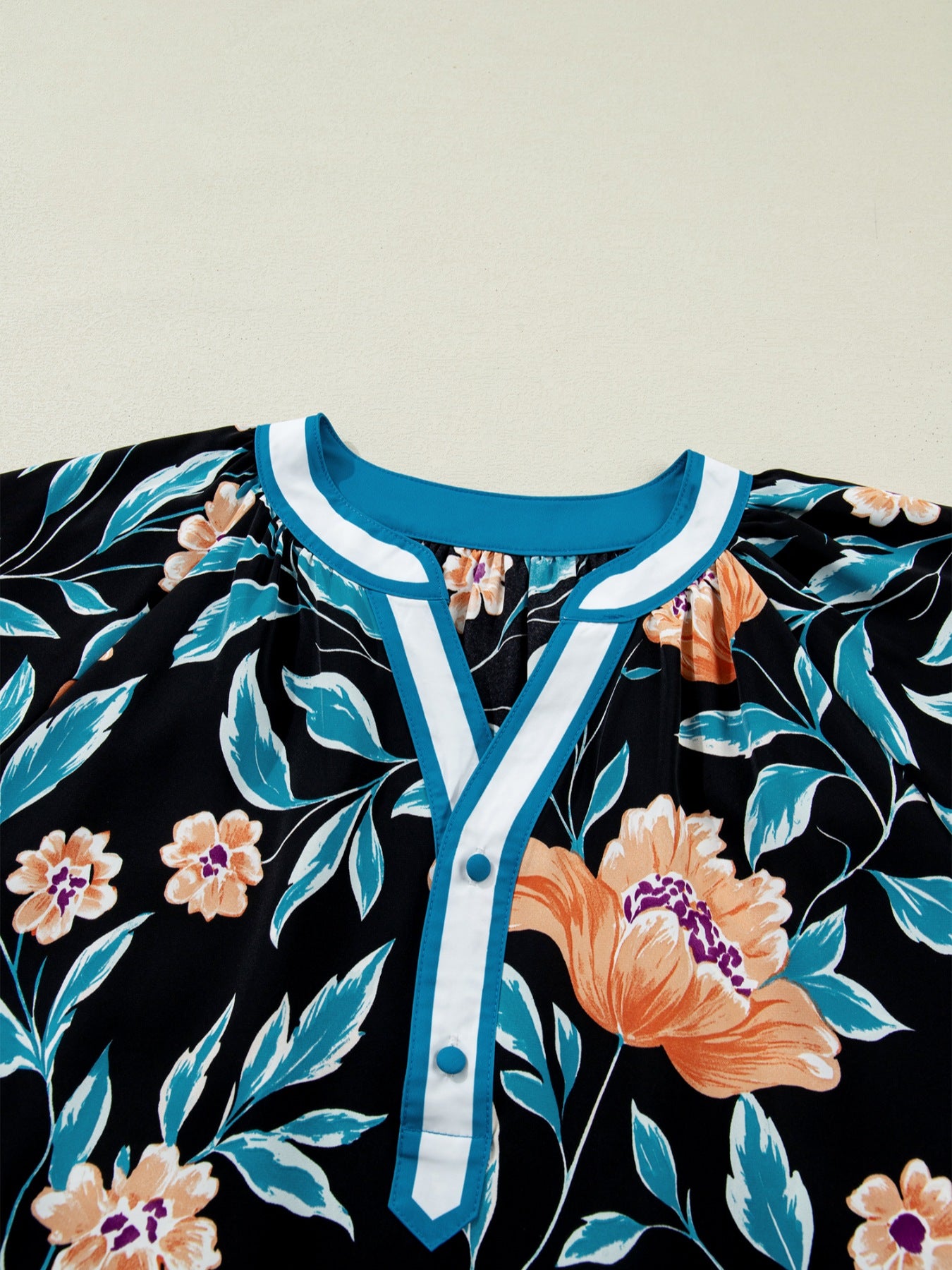 Black floral print blouse with bubble sleeves and button-down detail.