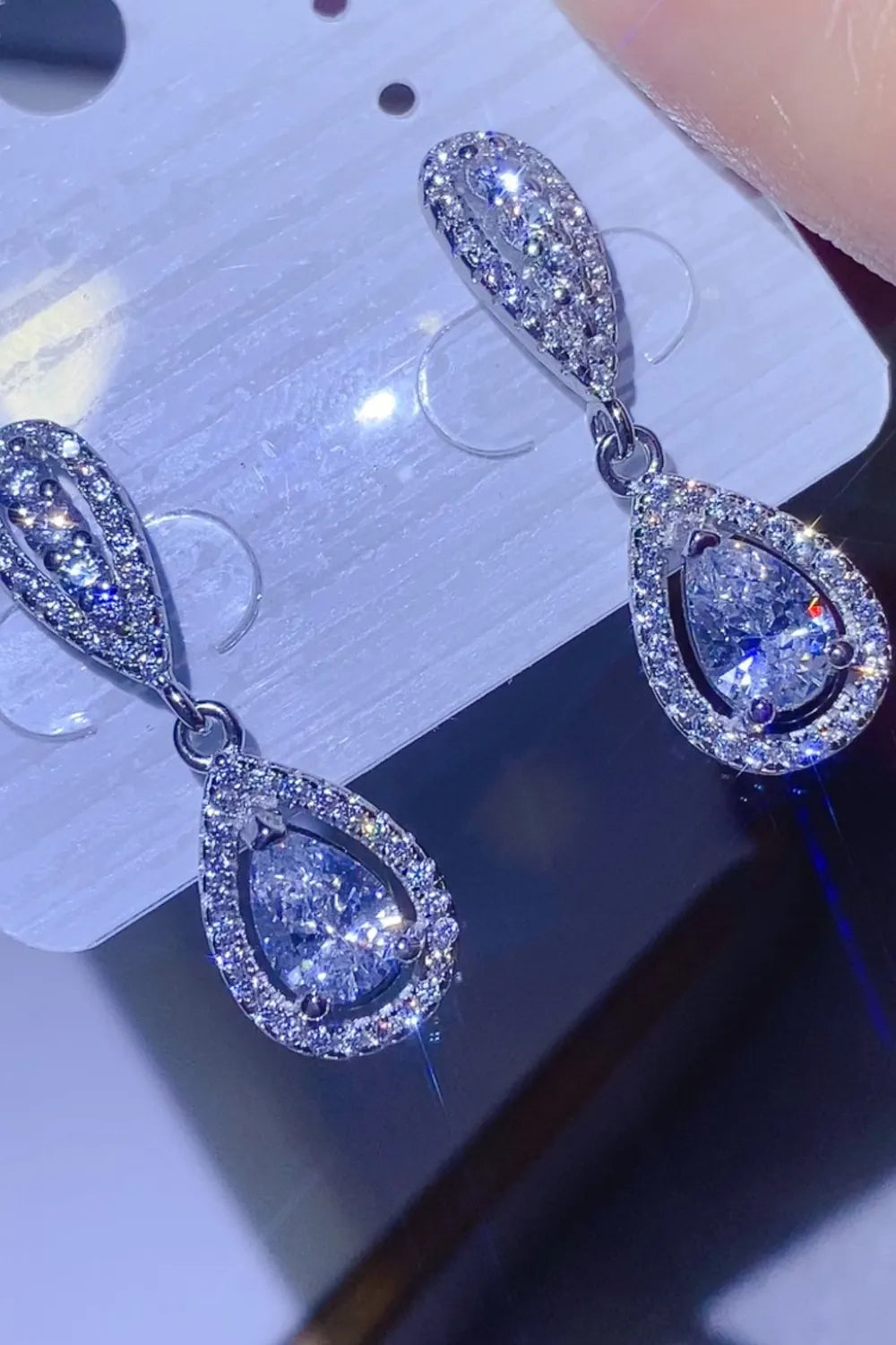 Silver pavé halo moissanite drop earrings with pear-shaped center stones.