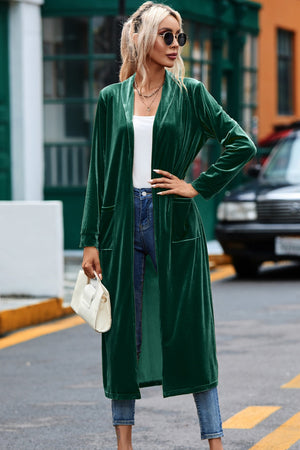 Dark green velvet duster coat with pockets and open front, worn with jeans.