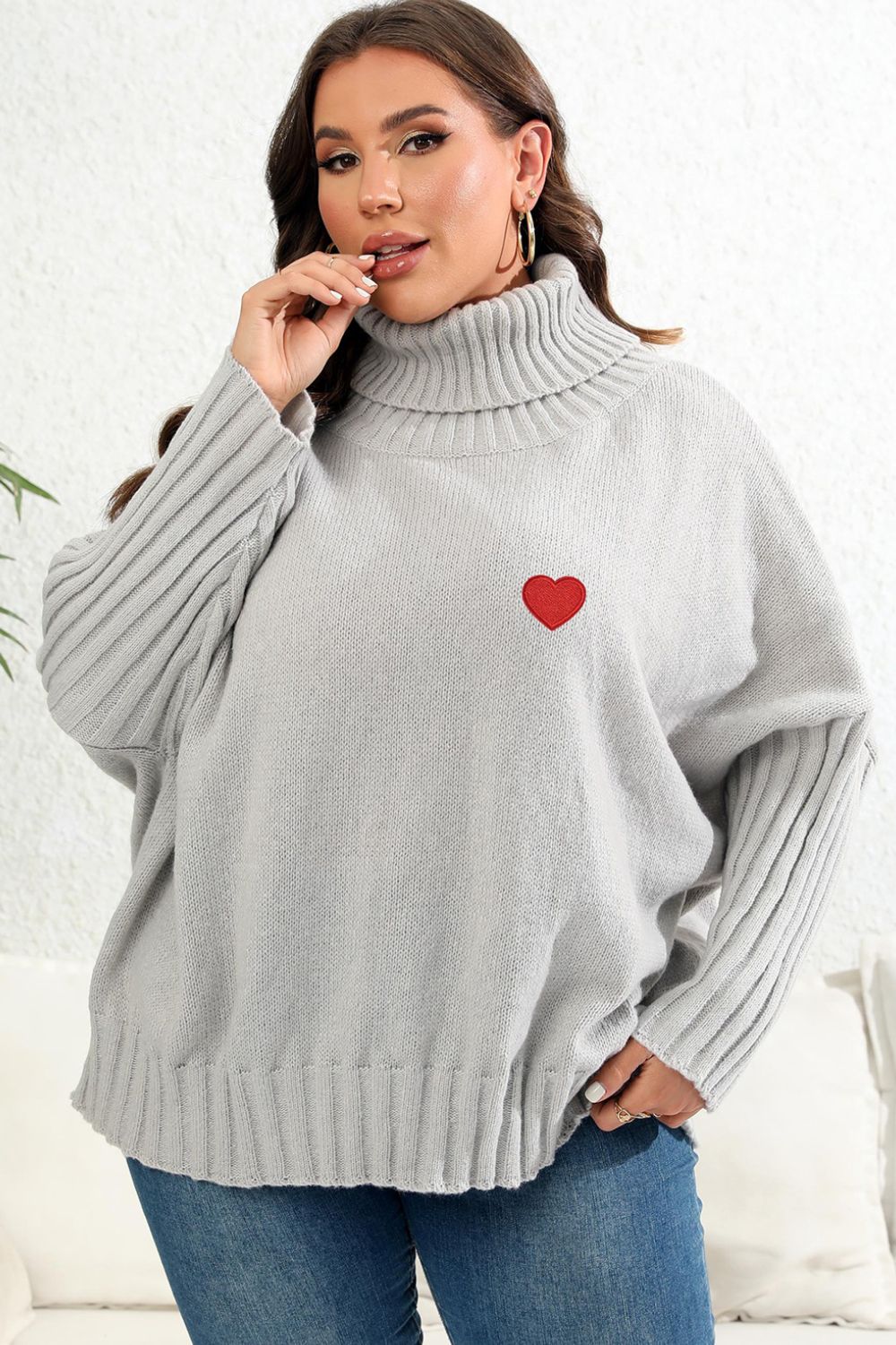 Light Gray knit turtleneck sweater with batwing sleeves and a red heart appliqué.
