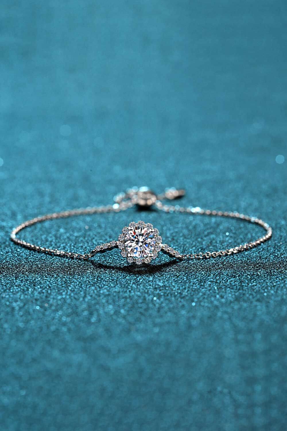 Silver adjustable bracelet with a round, sparkling center stone surrounded by a floral halo of smaller stones.