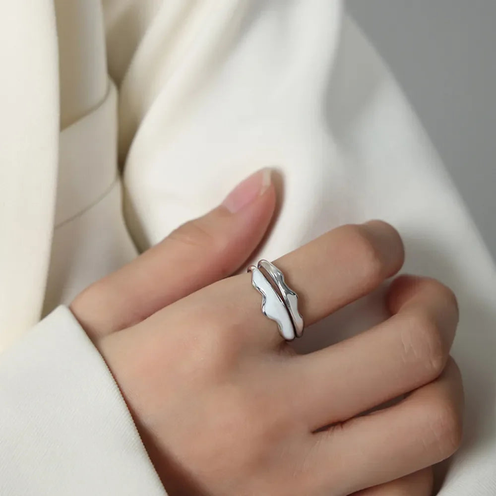 Sculpted enamel wave ring in silver and white, featuring a fluid, organic design.