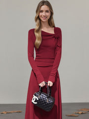 Burgundy ribbed maxi dress with asymmetrical neckline and floral detail.