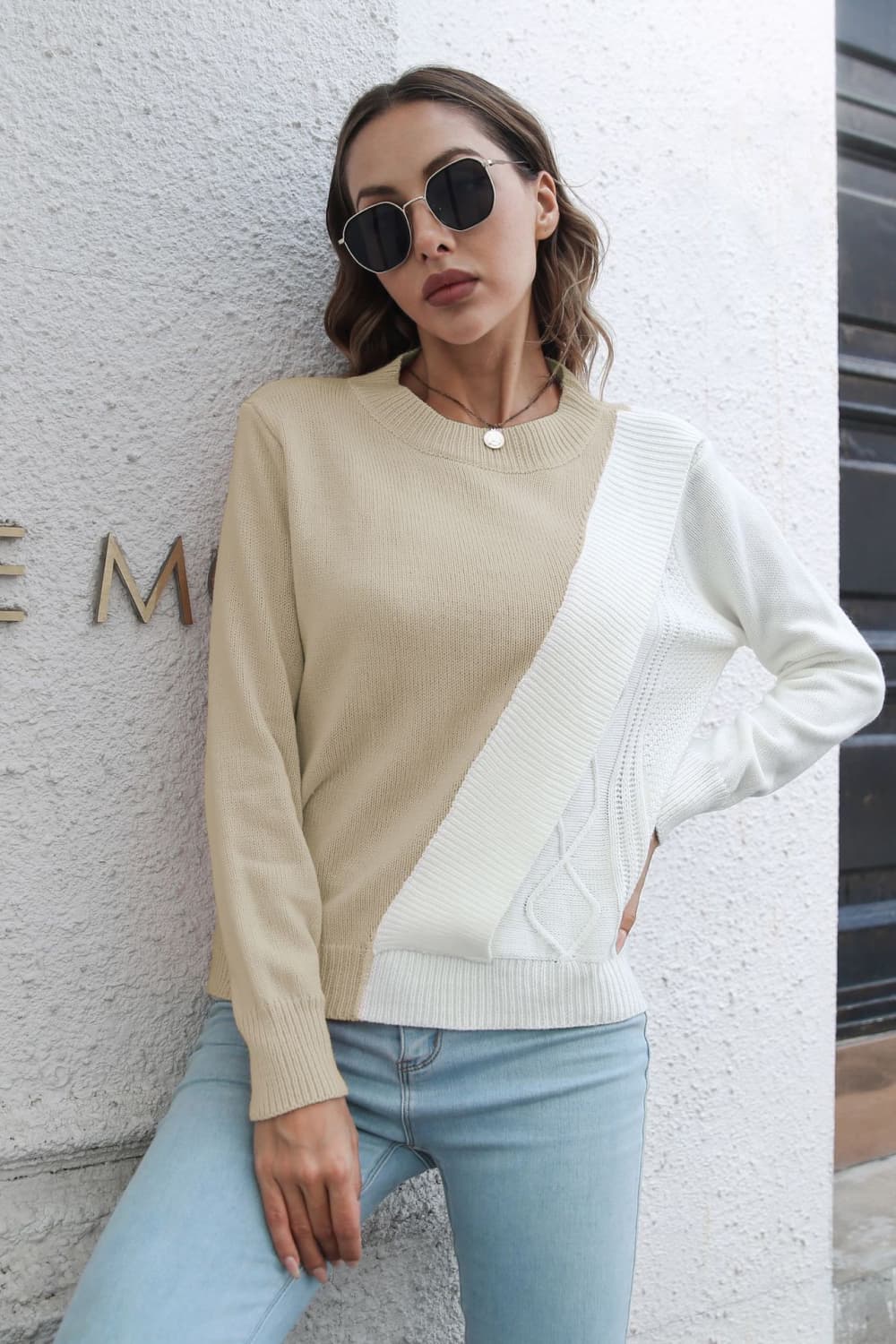 Beige and white acrylic sweater with diagonal colorblock and cable knit details.