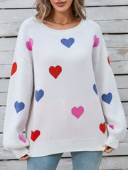 White knit sweater with bubble sleeves and a scattered heart motif in pink, red, and blue.