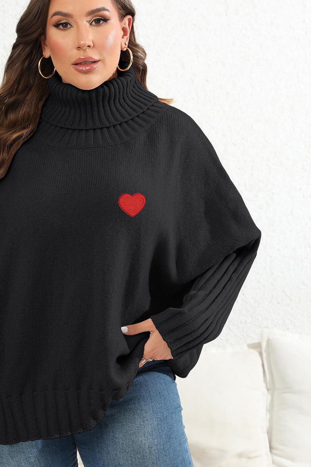 Black turtleneck sweater with red heart appliqué and batwing sleeves.