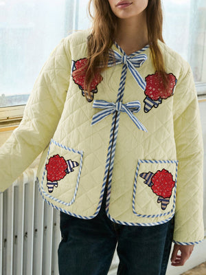 Pastel yellow quilted jacket with floral appliqué, blue striped trim and bows.