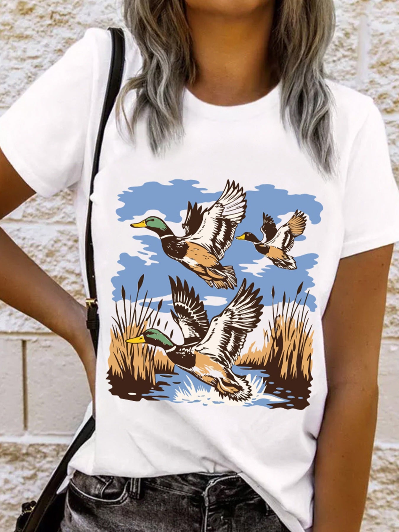 White cotton tee with a graphic of three ducks flying over reeds and water.