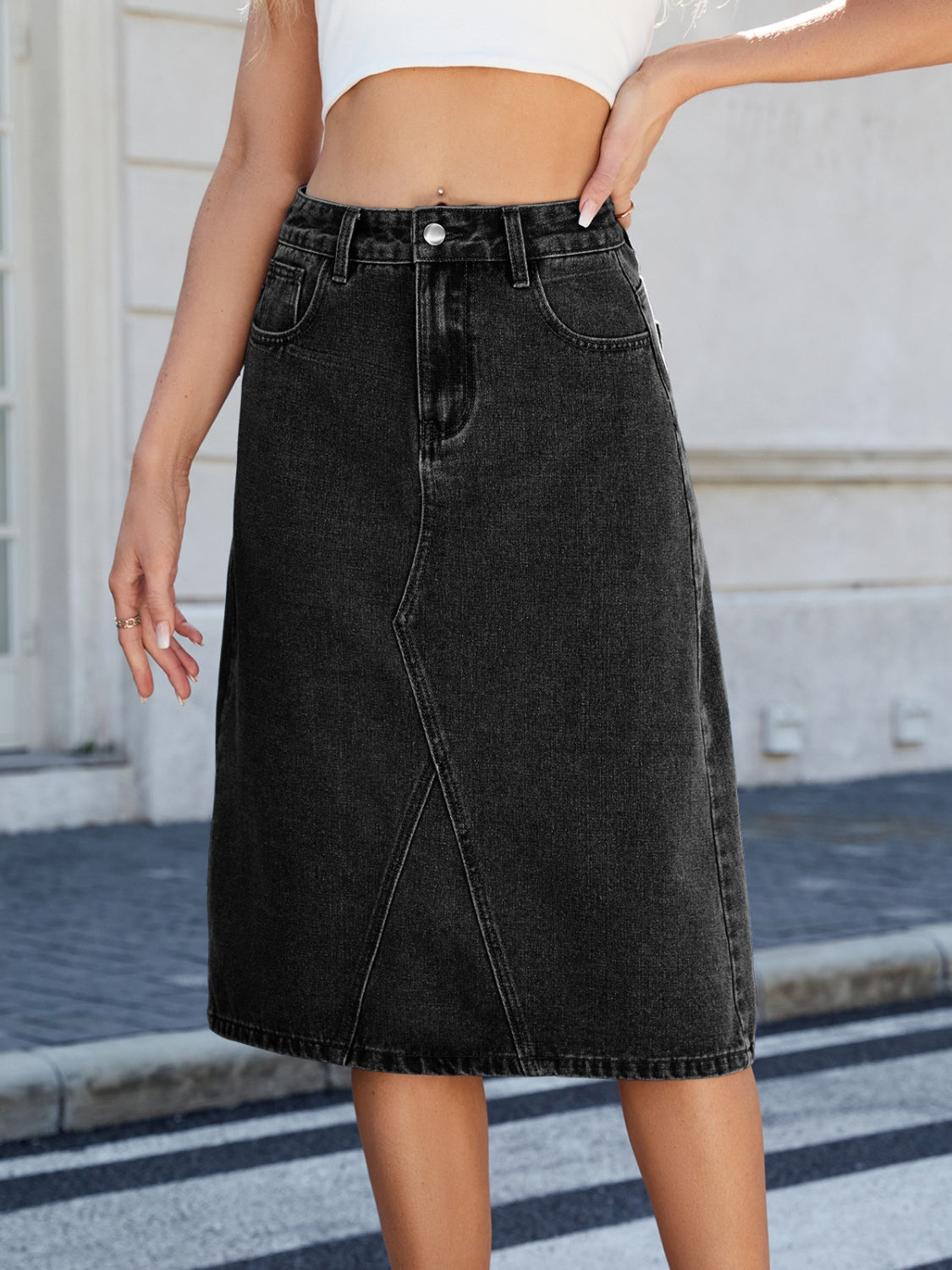 Black denim midi skirt with panel seams and a raw hem.