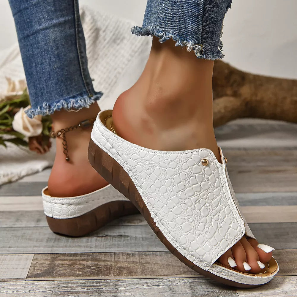 White glossy crocodile-embossed wedge sandals with a slip-on design.
