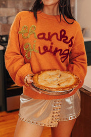 Orange knit sweater with sequin "Thanksgiving" graphic and crew neck.