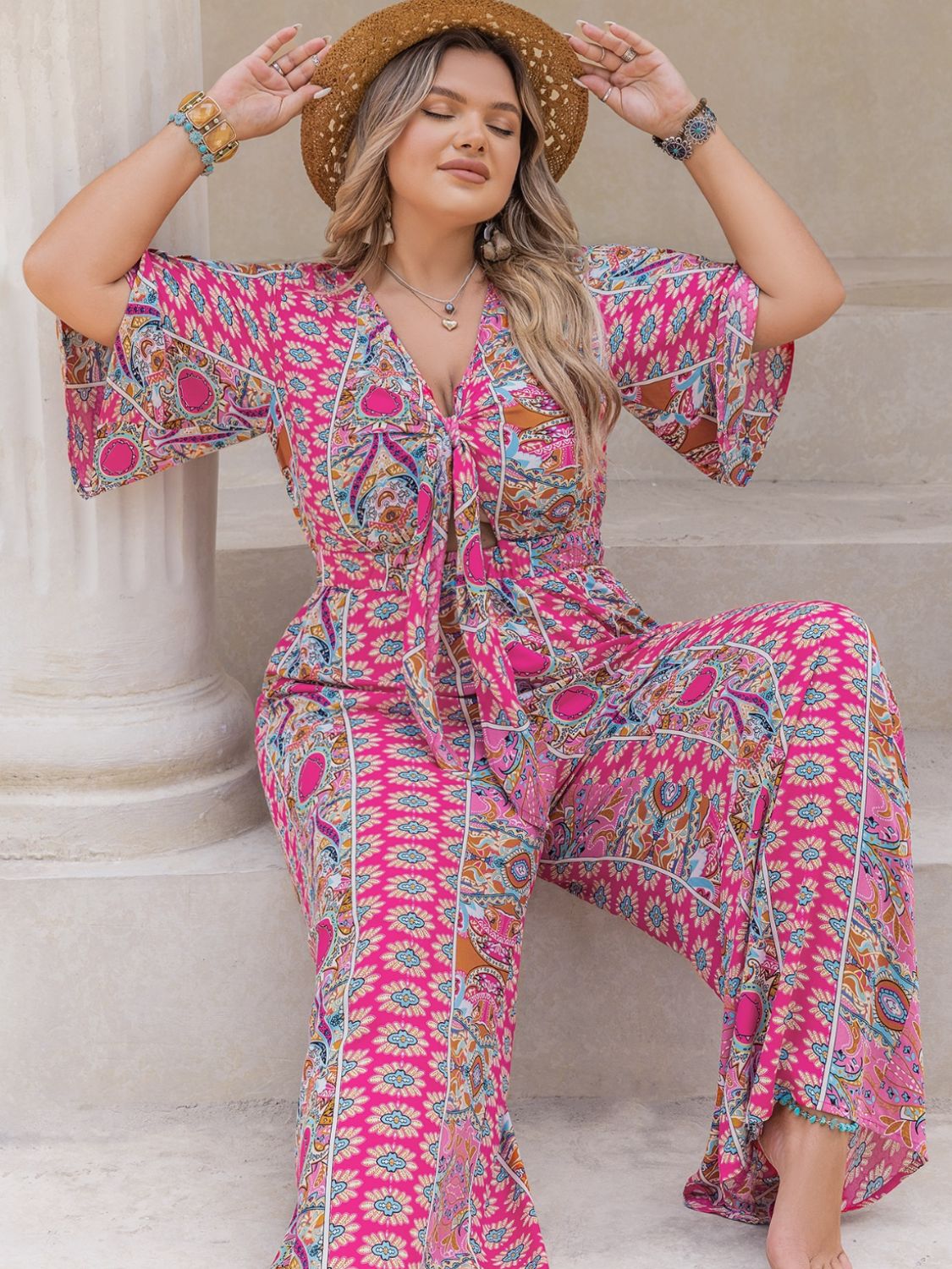 Bohemian tie-front palazzo jumpsuit in pink with bell sleeves and a vibrant paisley print.
