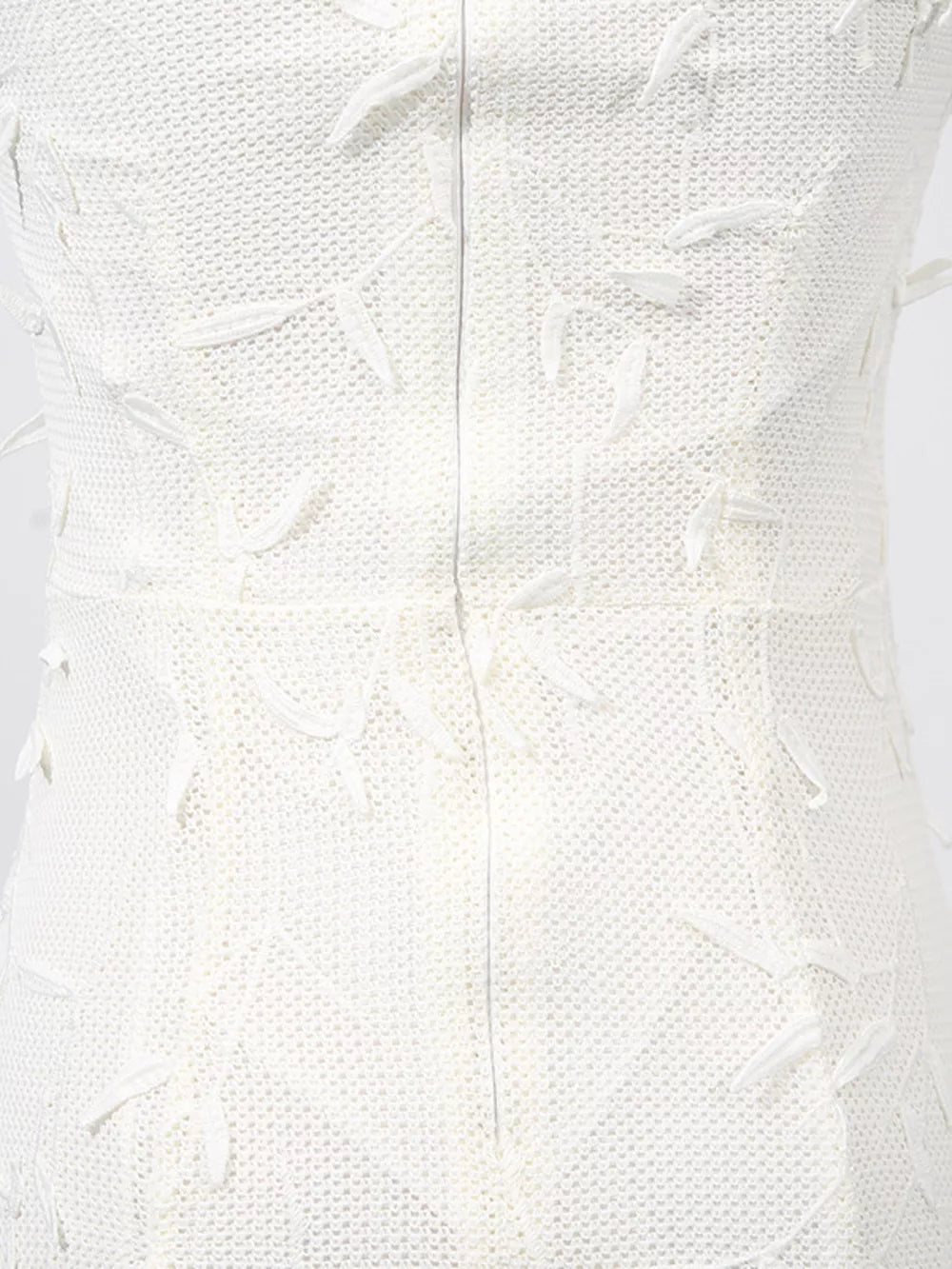 White midi dress with textured fabric and floral applique details.